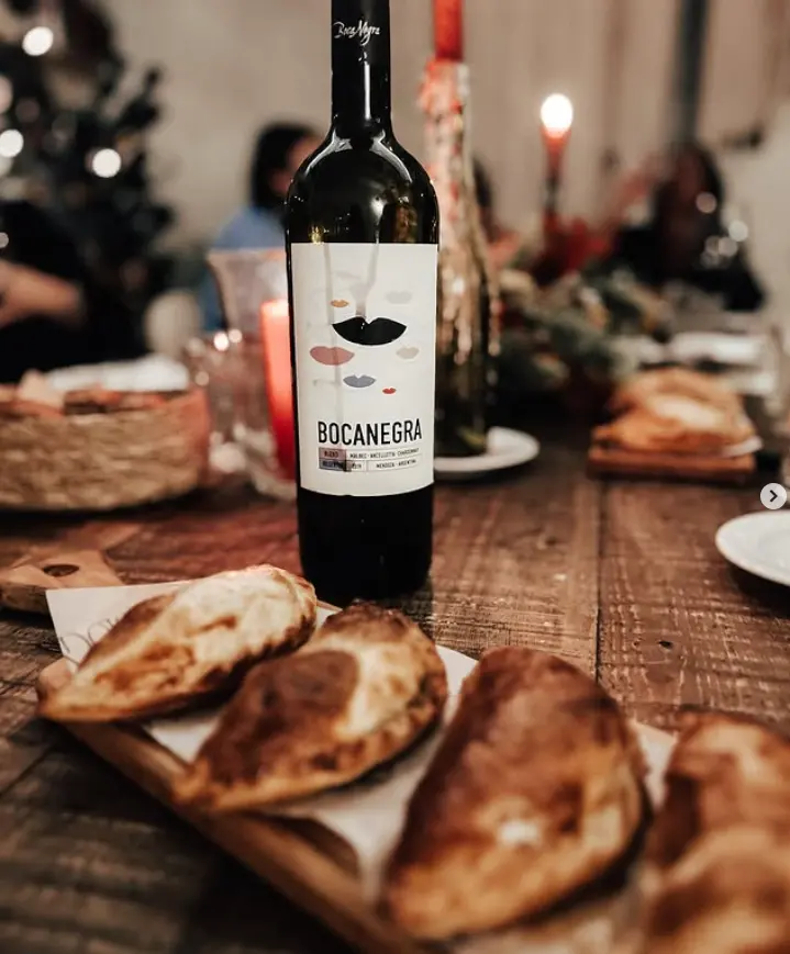 Botella de Bocanegra en una mesa compartida, con empanadas y velas